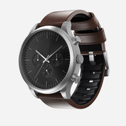 The Nomad Active Band Pro - 22mm Quick Release in Brown Horween leather with silver hardware is shown on a light gray background, featuring a black dial watch with three subdials and a stainless steel buckle.