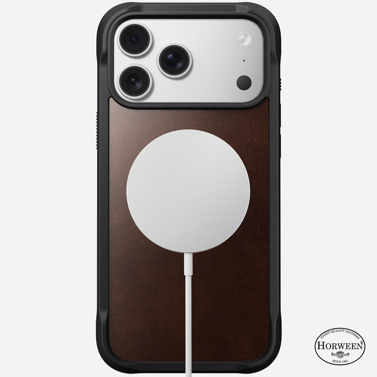 The Nomad Rugged Leather Case for iPhone 17 Pro Max in Rustic Brown features a Horween leather panel with black edges, MagSafe-compatible round charger attached, and displays the Horween logo at the bottom right.