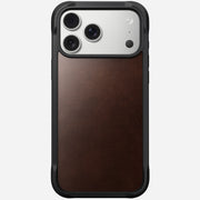 The Nomad Rugged Leather Case for iPhone 17 Pro Max in Rustic Brown features a black frame, premium Horween leather back, MagSafe compatibility, and precise cutouts for the phone's triple cameras and flash in the top left corner.