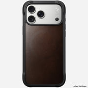 A Nomad Rugged Leather Case for iPhone 17 Pro Max in Rustic Brown Horween leather is shown upright, featuring a triple camera and black frame. "After 100 Days" appears in the bottom right corner.