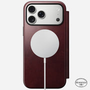 A Nomad Modern Leather Folio for iPhone 17 Pro Max in Burgundy Horween leather features MagSafe, three camera lenses, a Horween logo on the bottom right, and has a wireless charging pad attached to the back.