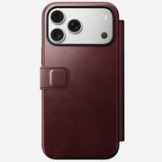 The iPhone 17 Pro Max features the Nomad Modern Leather Folio in Burgundy Horween leather, with a left-side clasp, MagSafe compatibility, and three rear camera lenses.