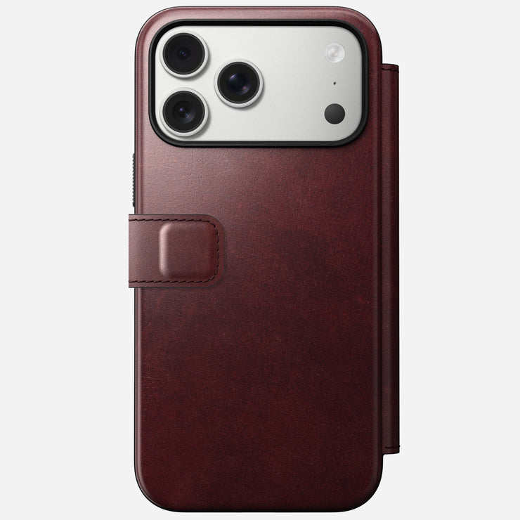 The iPhone 17 Pro Max features the Nomad Modern Leather Folio in Burgundy Horween leather, with a left-side clasp, MagSafe compatibility, and three rear camera lenses.