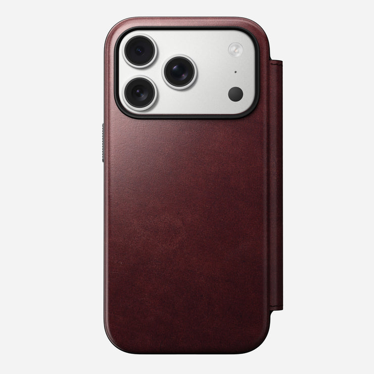 The Nomad Modern Leather Folio for iPhone 17 Pro in Burgundy, made with Horween leather, features a fold-over cover and MagSafe compatibility, shown protecting a smartphone with three rear cameras against a plain white background.