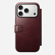 The Nomad Modern Leather Folio for iPhone 17 Pro, shown in Burgundy Horween leather, features a magnetic clasp and MagSafe compatibility. It fits a phone with three rear cameras and flash, displayed on a plain white background.