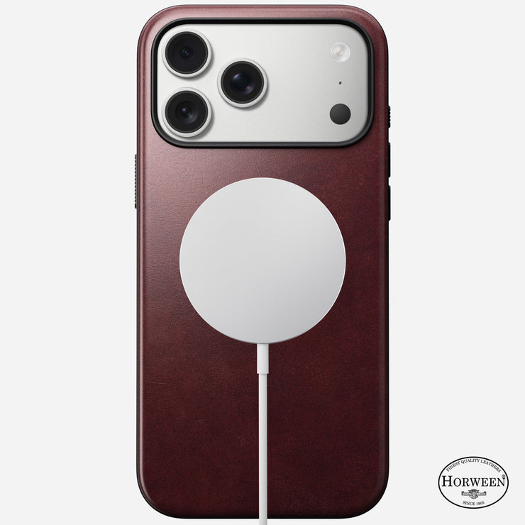 An iPhone 17 Pro Max in a Nomad Modern Leather Case (Burgundy, Horween), featuring 8ft drop protection and the Horween logo at the bottom right, with a white circular MagSafe charger attached to the back.