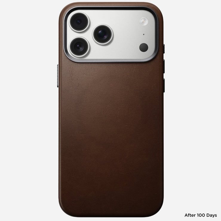 A Nomad Traditional Leather Case in brown is shown on the iPhone 17 Pro Max, revealing three rear cameras and light wear after 100 days. "After 100 Days" appears at the bottom right. MagSafe charging support adds convenience.