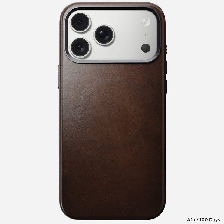 A Nomad Traditional Leather Case in Rustic Brown Horween is shown on an iPhone 17 Pro Max with a triple camera and a silver camera area, viewed from the back. The text "After 100 Days" appears in the bottom right corner.