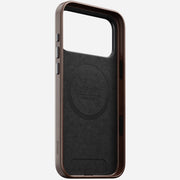 The Nomad Traditional Leather Case for iPhone 17 Pro Max in Rustic Brown uses Horween leather, features brown and black colors, a large camera cutout, side buttons, MagSafe compatibility, and engraved branding on the lower side and inside circle.