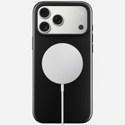 A Nomad Modern Case - iPhone 17 Pro Max in Vulcan Black with TPU bumper (8ft drop protection), triple cameras, and a silver MagSafe charger connected by a white cable, shown on a plain white background.