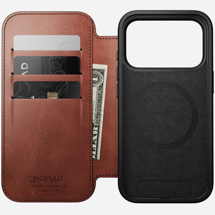 Nomad’s Modern Leather Folio for iPhone 17 Pro in Olde Dublin Horween leather is shown open, revealing three card slots and a cash pocket with cards and a dollar bill. Next to it is a black MagSafe case featuring a circular magnet area.