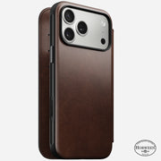 The Nomad Modern Leather Folio for iPhone 17 Pro Max features rustic brown Horween leather with visible stitching, a fold-over cover, Horween logo at the bottom right, and is MagSafe compatible for wireless charging.