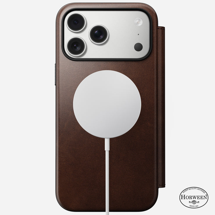 A Nomad Modern Leather Folio for iPhone 17 Pro Max in Rustic Brown Horween leather features 8ft drop protection, shows the triple-lens camera, and has a MagSafe charger attached; the Horween logo appears at the bottom right.