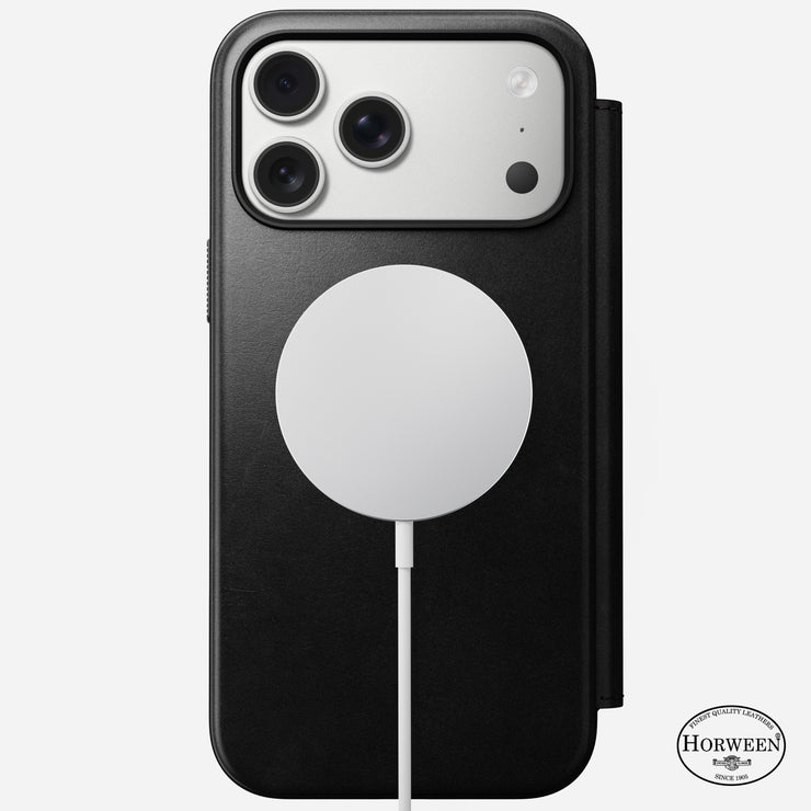 A Nomad Modern Leather Folio in black Horween leather is wirelessly charging an iPhone 17 Pro Max with three cameras; the Horween Leather Co. logo is visible at the bottom right of the case.