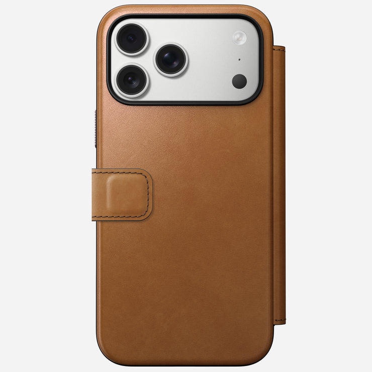 The Nomad Modern Leather Folio for iPhone 17 Pro Max in English Tan-C features full-grain brown leather, a magnetic clasp, and MagSafe compatibility. Shown closed, it displays the phone’s triple-camera and flash on the back.