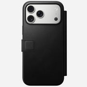 The Nomad Modern Leather Folio in black for iPhone 17 Pro Max is partially open, showcasing the camera lenses and flash against a plain light background.