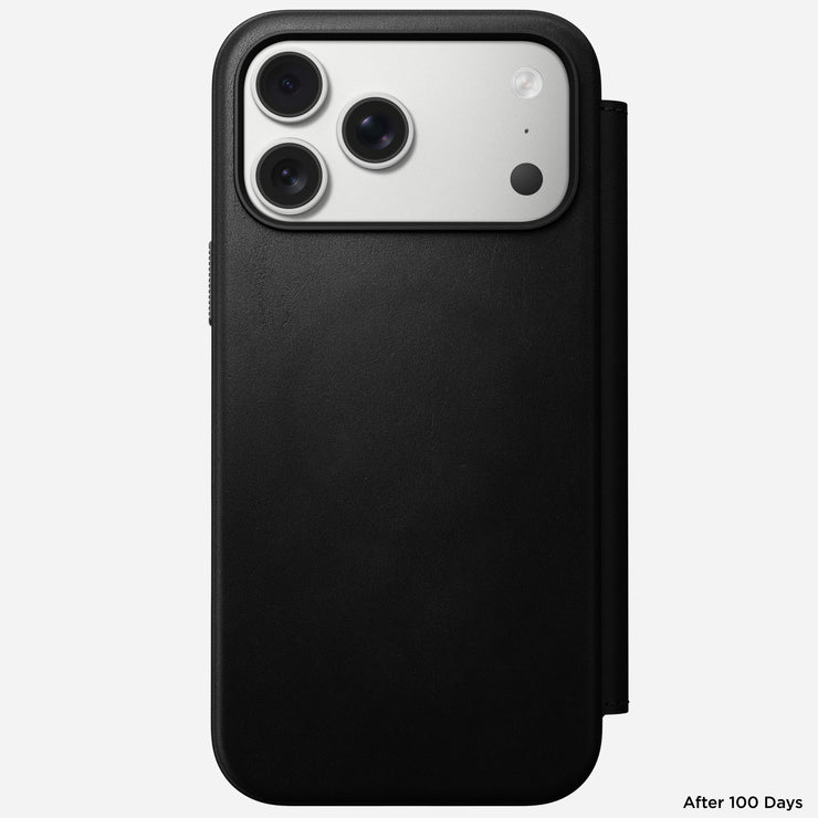 The Nomad Modern Leather Folio for iPhone 17 Pro Max in black, made from sustainably sourced leather, partially covers a triple-camera phone on a white background. "After 100 Days" appears in the bottom right corner.