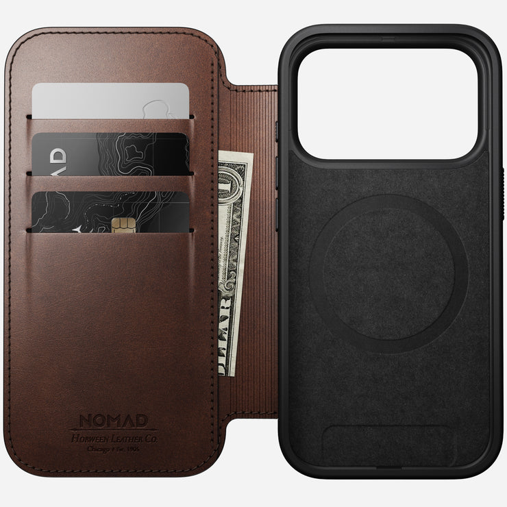 A Nomad Modern Leather Folio for iPhone 17 Pro in Rustic Brown Horween leather, with three card slots holding two cards and a folded bill, sits beside a black MagSafe-compatible case with a visible MagSafe ring.