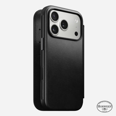 An iPhone 17 Pro is shown in a black Horween leather Nomad Modern Leather Folio case. MagSafe compatible, the case covers the back and sides, exposes three camera lenses, and displays the Horween logo at the bottom right.