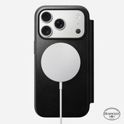 An iPhone 17 Pro with three cameras is in a black Horween leather Nomad Modern Leather Folio; a circular wireless charger attaches to the MagSafe-compatible back, and the Horween logo appears at the bottom right.