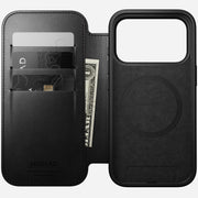 The Nomad Modern Leather Folio for iPhone 17 Pro in Black Horween leather features card slots holding two cards and a folded bill, shown open to display the phone and cardholder sections. MagSafe compatible for effortless wireless charging.