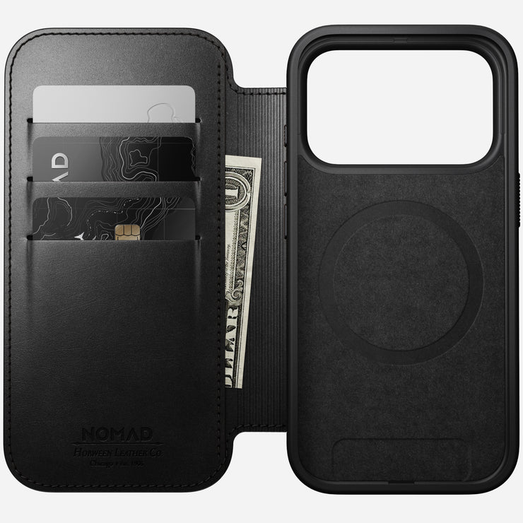 The Nomad Modern Leather Folio for iPhone 17 Pro in Black Horween leather features card slots holding two cards and a folded bill, shown open to display the phone and cardholder sections. MagSafe compatible for effortless wireless charging.