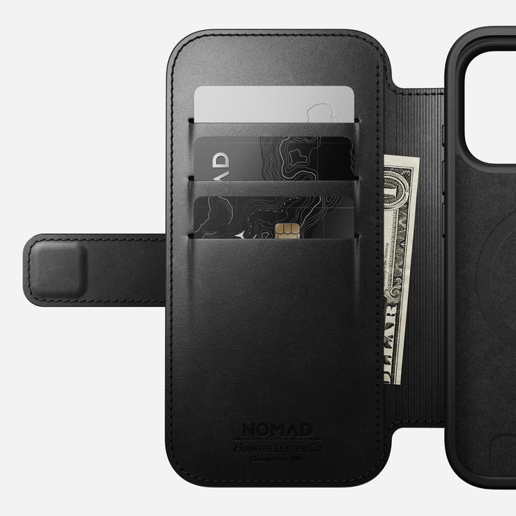 Nomad’s Modern Leather Folio for iPhone 17 Pro in black Horween leather, shown open with three card slots (holding two cards and a folded US dollar bill) and the phone compartment on the right.
