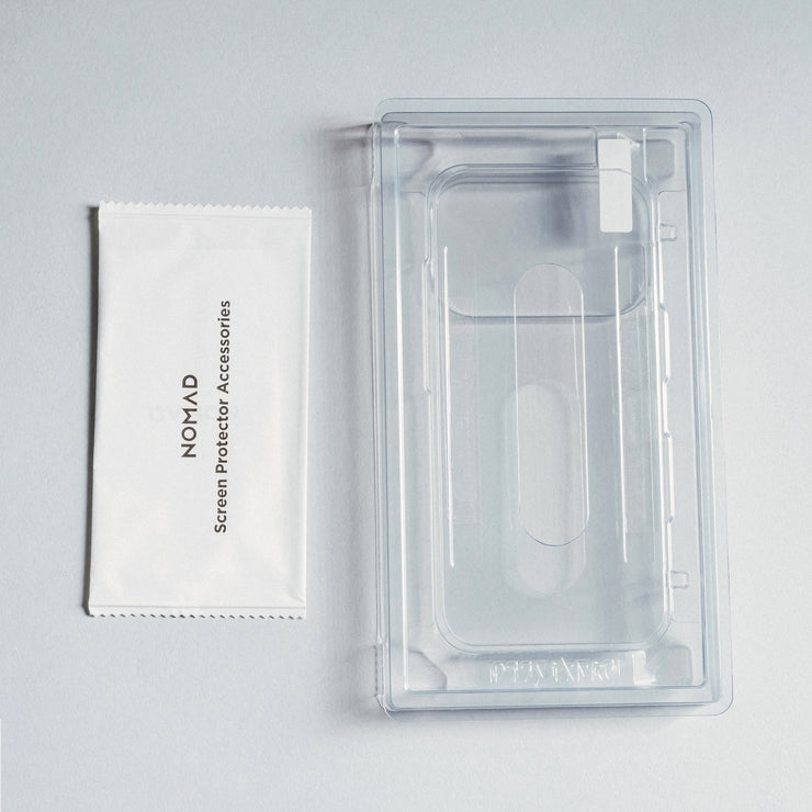 A Nomad Screen Protector - iPhone 17 Pro and its labeled accessories packet rest on a light gray surface; the protector is clear and scratch-resistant.
